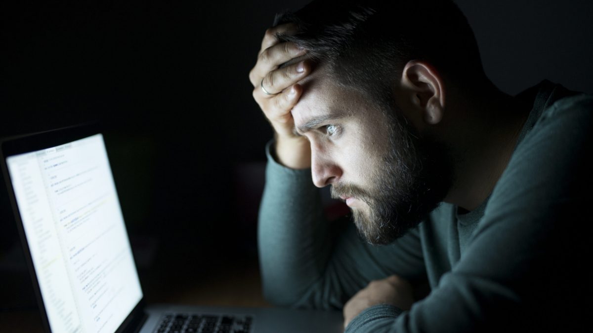 Man in front of the laptop reading and being concentrated.